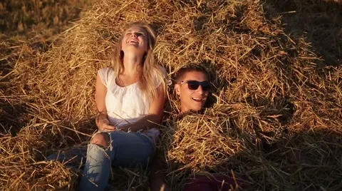 Man and woman on the haystack, sunset illuminates their faces. Stock Footage 61816047