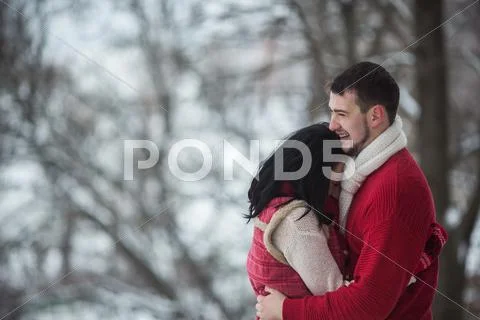 Man and woman hugging in snow-covered park Stock Photos