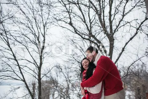 Man and woman hugging in snow-covered park Stock Photos