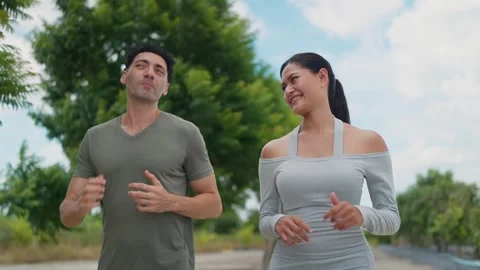 Man and woman jog side by side through park Vídeo Stock 345216341