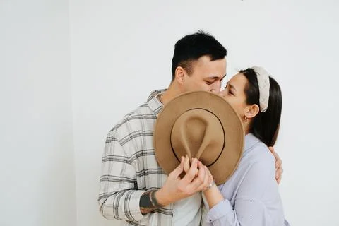 Man and woman kissing hiding behind a hat Stock Photos