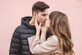 The man and a woman kissing on the pink wall background Photo