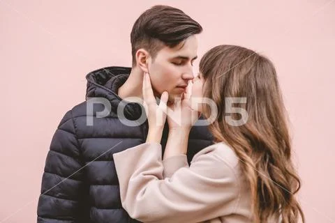 The man and a woman kissing on the pink wall background Stock Photos