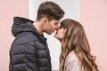 The man and a woman kissing on the pink wall background Photo