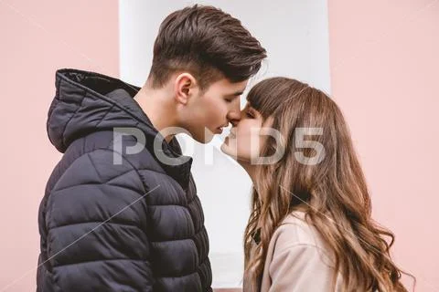 The man and a woman kissing on the pink wall background Stock Photos