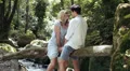 a man and a woman kissing sitting on a tree trunk near the river HD Footage