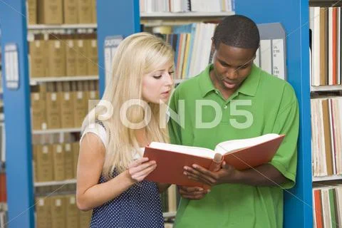 Man and woman in library reading book (depth of field) Stock Photos