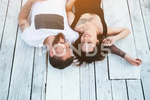 Man and woman lie on the wooden floor Stock Photos
