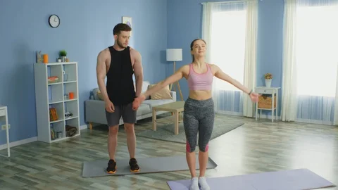 Man and Woman Practice Basic Yoga and Have Fun at Home Stock Footage 129973070