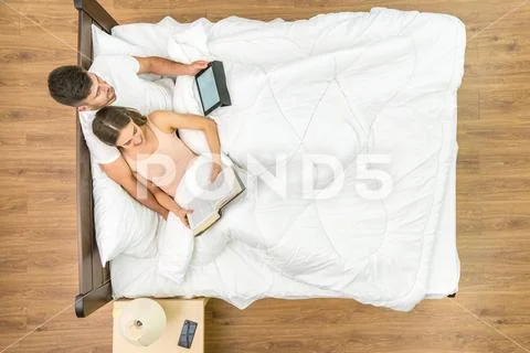 The man and woman read on the bed. View from above Stock Photos