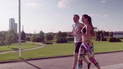 Man and woman running in city park Stock Footage