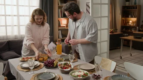 Man and Woman Setting Dining Table with Food for Dinner Stock Footage 340338282