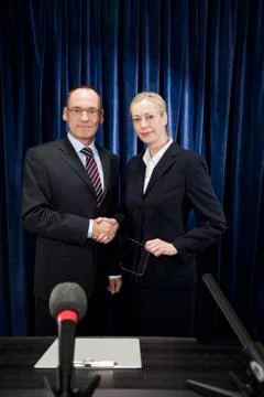 A man and a woman shaking hands at a press conference Stock Photos