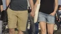 Man and woman in shorts holding hands while strolling down street in slow motion HD Footage