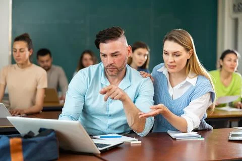 Man and woman solving a problem together on a laptop while studying in Stockfoto's