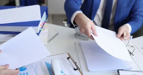 Man and woman sorting documents with hole punch and stapler and putting them in Video stock 245562090