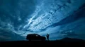 The man and woman standing near a car against the cloud stream. time lapse 4k or 4k+ Resolution