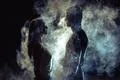 The man and woman standing in smoke on the dark background Photo