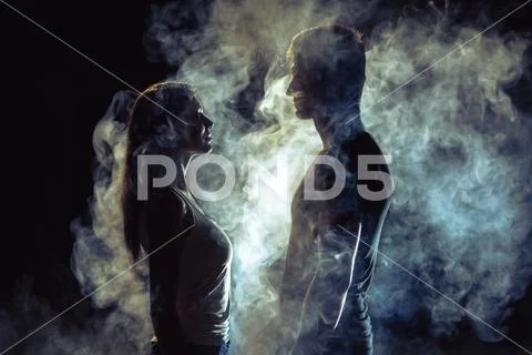 The man and woman standing in smoke on the dark background Stock Photos