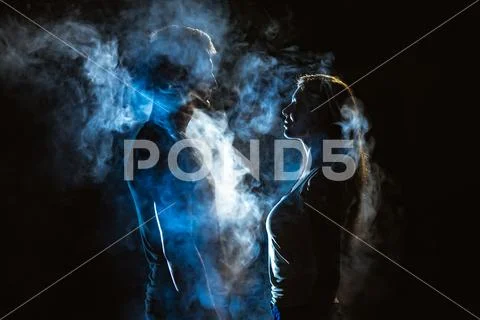The man and woman standing in smoke on the dark background Stock Photos