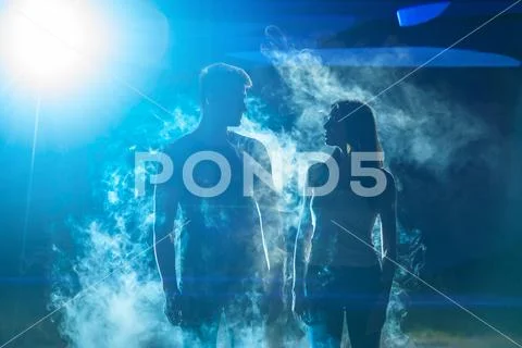 The man and woman standing in the smoke on a bright light background Stock Photos