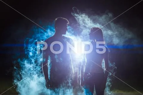 The man and woman standing in the smoke on a bright light background Stock Photos