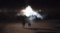 The man and woman walking in a night park near the smoke cloud. slow motion 4k or 4k+ Resolution