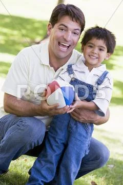 Man and young boy outdoors with football smiling Stock Photos