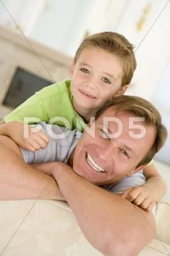 Man and young boy sitting in living room smiling Stock-Fotos