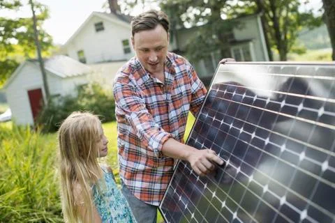 A man and a young girl looking at a solar panel Stock Photos