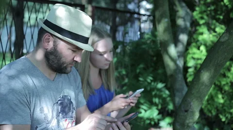 Man and young woman sitting outside and using smartphones Stock Footage 59144929