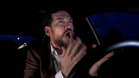 Man angry driving car in traffic at night Stock Footage 130080004