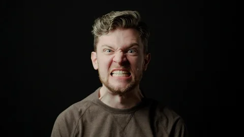 Man with angry face on black backdrop, greed, anger, slow motion, slow-mo Stock Footage 125653021