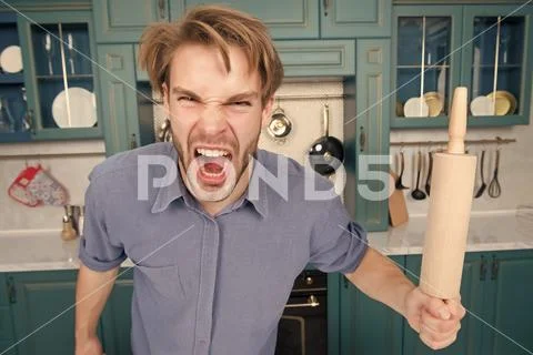 Man with angry face shout with rolling pin in kitchen Stock Photos