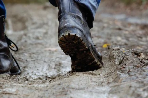 A man in ankle boots walking through the mud, forest road, close-up Stock Photos