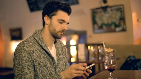 Man answer cellphone while sitting in a bar and talking with someone Stock Footage 70126470