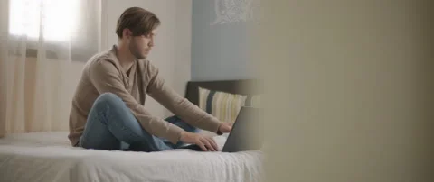 A man answering his phone while working on a computer from home. Stock Footage 135095984