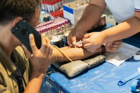 Man answering the phone while having blood sampling. Stock Photos