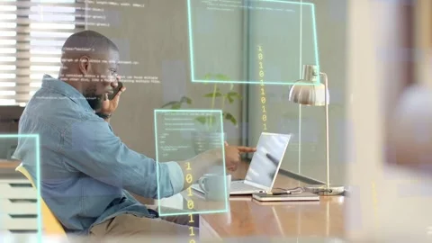 Man answering phone while tapping laptop in tech office, holographic code over Stock Footage 333657240