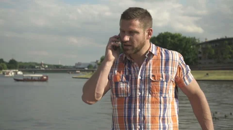 Man answering smartphone by the river 库存影片 52698699