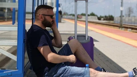 Man answers cellphone while sitting on the platform and looks really angry Stock Footage 78653787