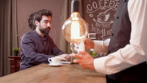 Man answers a phone call while working on his computer and drinking coffee 스톡 동영상 106701815