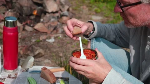 A man with appetite eats canned fish in tomato sauce with a fork. Outdoor picnic Stock Footage 163713167