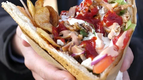 A man appetizingly holds kebab in a bread pita filled with chicken, vegetables Stock Footage 304998771