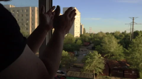 A man applauds in the window of the doctors who save people from the coronavirus Stock Footage 130940737