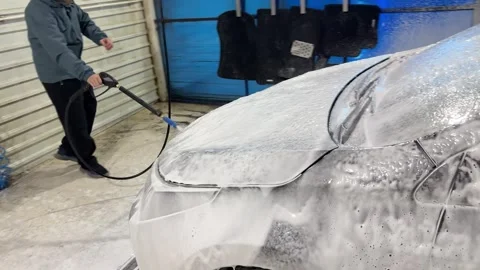 A man applies a cleaning solution with a high pressure cleaner at a car wash Stock Footage 308818890
