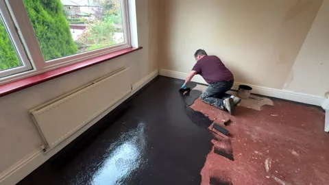 Man applies damp proof membrane coating to house floor with a trowel Stock Footage 292999850
