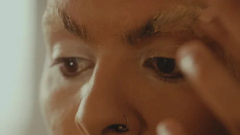 Man applies face putty to eyebrows and pats hair down Stock Footage 275652964