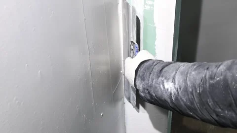 Man applies joint compound to drywall in room renovation process in evening Vídeo Stock 326376363