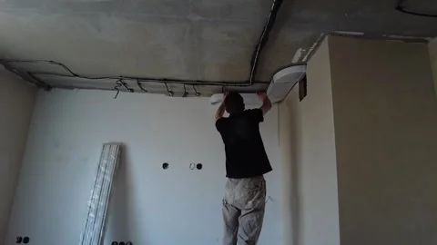 Man applies plaster to the wall in a room renovation project in an indoor space 스톡 동영상 333443604